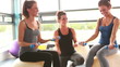 Trainer helping women on exercise balls lifting weights
