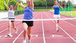 Three woman running on a track and crossing finish line