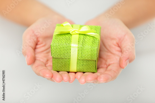 Photo: Colourful green gift in cupped hands Colourful green gift in cupped hands