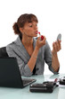 Woman applying lipstick at the office