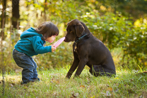 Photo: Young child playing fetch with dog Young child playing fetch with dog