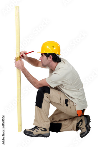 Photo: Tradesman marking a measurement on a wooden plank Tradesman marking a measurement on a wooden plank