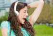 Photo: Beautiful Young Woman with Headphones Outdoors. Enjoying Music Beautiful Young Woman with Headphones Outdoors. Enjoying Music