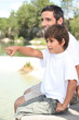 Father and son sitting by a lake