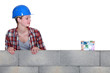 Female builder looking at a house made of money