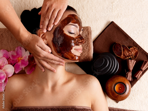 Photo: Spa massage for woman with facial mask on face Spa massage for woman with facial mask on face