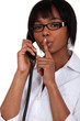 Woman talking on the phone and holding her finger to her lips