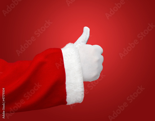 Photo: Santa Claus hand showing thumbs up over red background Santa Claus hand showing thumbs up over red background
