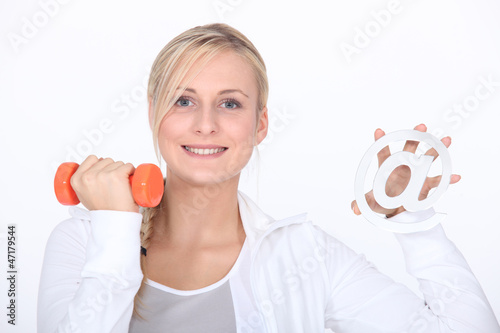 Photo: Young woman holding at sign and dumbbell Young woman holding at sign and dumbbell
