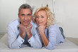 Man and woman lying with their heads propped up on their hands