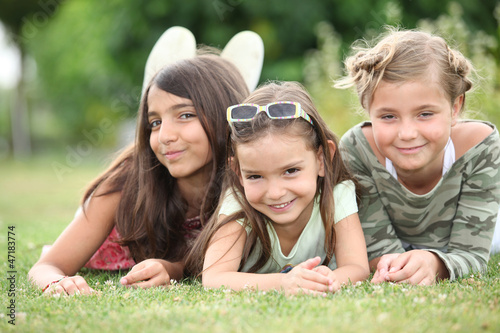 Photo: Three young girls lying on the grass Three young girls lying on the grass