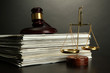 Golden scales of justice, gavel and books on grey background