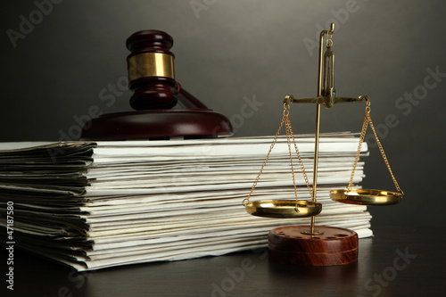 Photo: Golden scales of justice, gavel and books on grey background Golden scales of justice, gavel and books on grey background