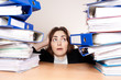 Frustrated businesswoman with stack of folders