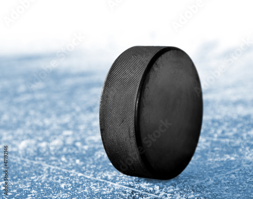 Photo: black hockey puck on ice rink black hockey puck on ice rink