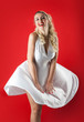 Blonde woman portrait with skirt flying on red background.