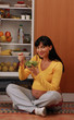 Divertida mujer embarazada comiendo ensalada en la cocina.