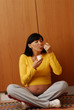 Divertida mujer embarazada comiendo yogurt en la cocina.