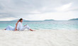 Photo: Young couple sitting on the beach near the seaside Young couple sitting on the beach near the seaside