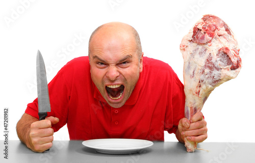 Photo: Angry hungry man (boss) with knife and raw bloody meat. Angry hungry man (boss) with knife and raw bloody meat.