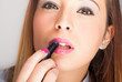 Young woman applying lipstick