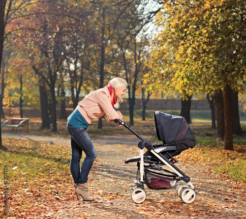 Photo: Young mother looking at her child in a stroller Young mother looking at her child in a stroller