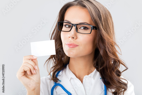 Photo: Young female doctor showing blank business card Young female doctor showing blank business card