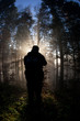 silhouette of man standing in sunbeams in forest