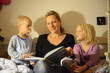 Mutter ließt Kindern im Bett eine Geschichte vor