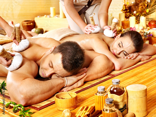 Photo: Man and woman getting herbal ball massage in spa. Man and woman getting herbal ball massage in spa.