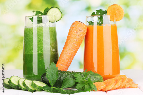 Photo: Fresh vegetable juices on wooden table, on green background Fresh vegetable juices on wooden table, on green background
