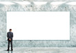 Business person standing near a blank billboard