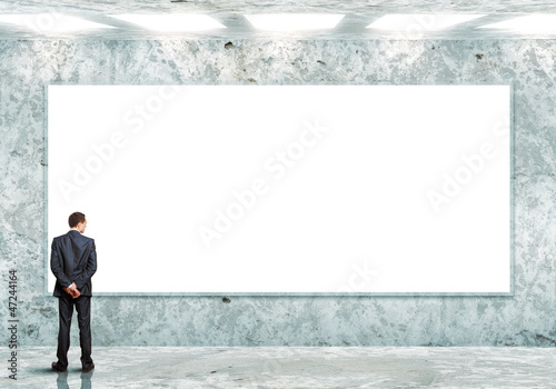 Photo: Business person standing near a blank billboard Business person standing near a blank billboard