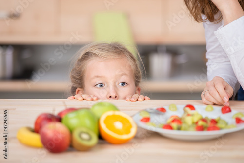 Photo: mädchen schaut neugierig auf obstsalat mädchen schaut neugierig auf obstsalat