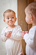 Baby standing against the mirror