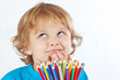 Young cute blond boy with color pencils on a white background