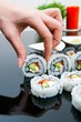 Hand holding sushi on black background