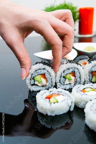 Photo: Hand holding sushi on black background Hand holding sushi on black background
