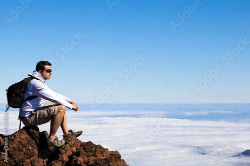 Photo: Young Man Having a Rest in a High Peak Over Clouds Young Man Having a Rest in a High Peak Over Clouds