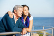Senior Man With Adult Daughter Looking Over Railing At Sea