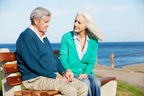 Photo: Senior Woman Comforting Depressed Husband Sitting On Bench Senior Woman Comforting Depressed Husband Sitting On Bench