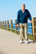Senior Man Walking Along Path By The Sea