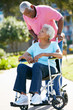 Senior Woman Pushing Unhappy Husband In Wheelchair