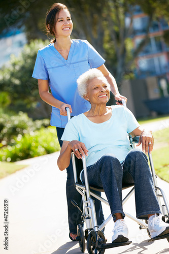 Photo: Carer Pushing Senior Woman In Wheelchair Carer Pushing Senior Woman In Wheelchair