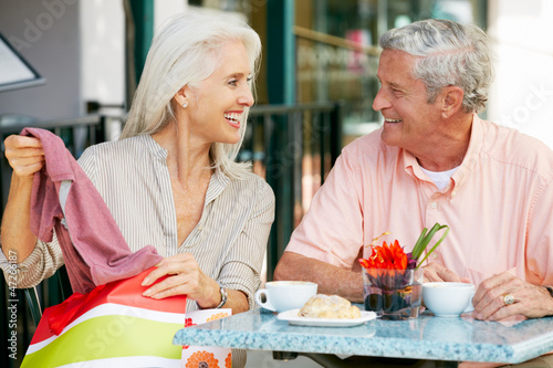 Photo: Senior Couple Enjoying Snack At Outdoor Café After Shopping Senior Couple Enjoying Snack At Outdoor Café After Shopping