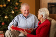 Senior Couple Exchanging Gifts In Front Of Christmas Tree