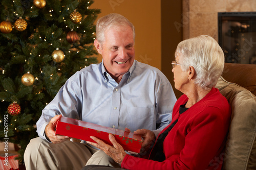 Photo: Senior Couple Exchanging Gifts In Front Of Christmas Tree Senior Couple Exchanging Gifts In Front Of Christmas Tree