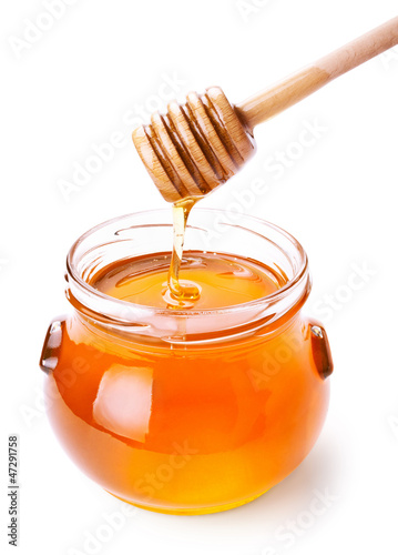 Photo: Glass jar of honey with wooden drizzler isolated on white Glass jar of honey with wooden drizzler isolated on white