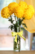bright yellow chrysanthemums in glass vase, on wooden table