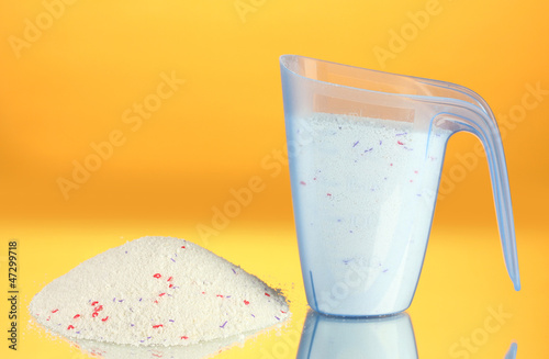 Photo: washing powder in a measuring cup, on yellow background washing powder in a measuring cup, on yellow background